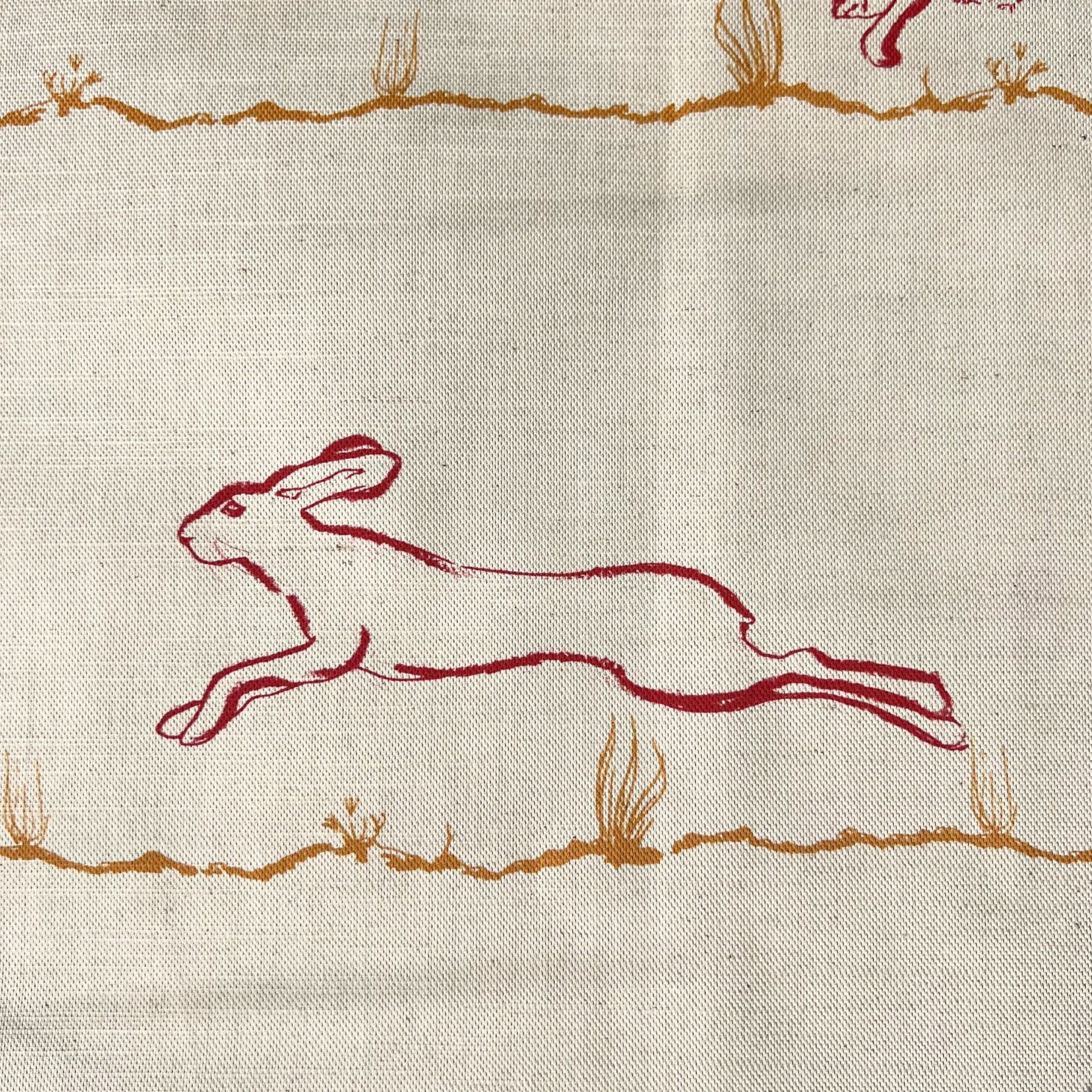 Fabric suitable for interiors projects with red outline of a hare printed on a natural undyed cloth
