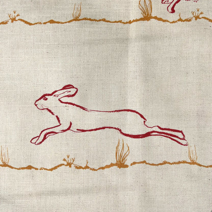 Fabric suitable for interiors projects with red outline of a hare printed on a natural undyed cloth