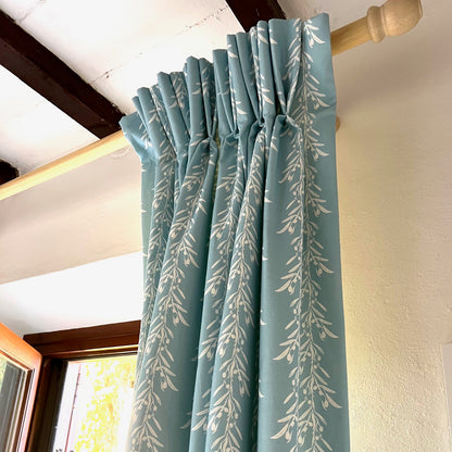 Blue curtains with a leaf pattern fabric.